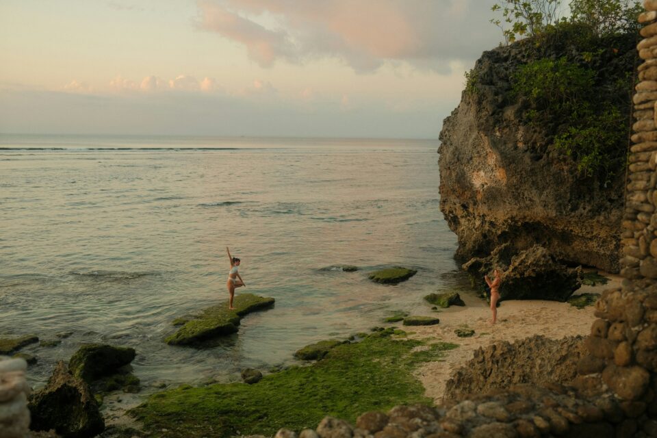 Pratique du yoga face à l'océan sur une plage préservée d'Indonésie — voyage bien-être Indonésie