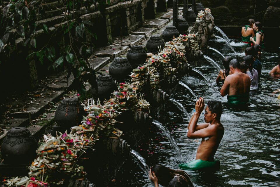 Fidèles balinais agenouillés en prière avec offrandes fleuries dans un temple hindou — bali authentique culture