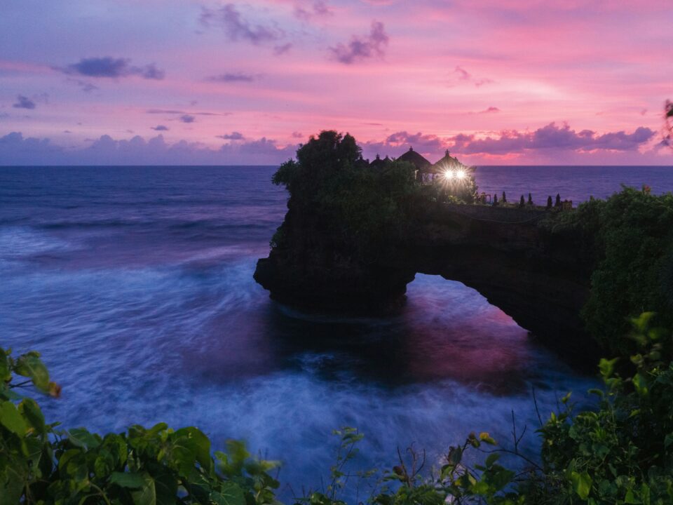 Temple hindou de Tanah Lot posé sur un rocher en arche face à l'océan au coucher du soleil — traditions balinaises